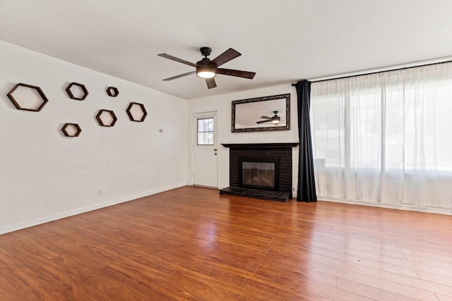 44129 Date Ave, Lancaster, CA 93534 - unfurnished living room featuring ceiling fan, a brick fireplace, wood finished floors, and baseboards