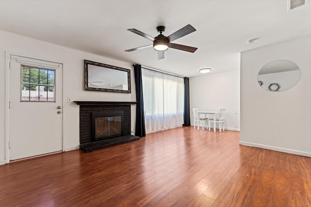 44129 Date Ave, Lancaster, CA 93534 - unfurnished living room with ceiling fan, wood finished floors, a brick fireplace, and baseboards