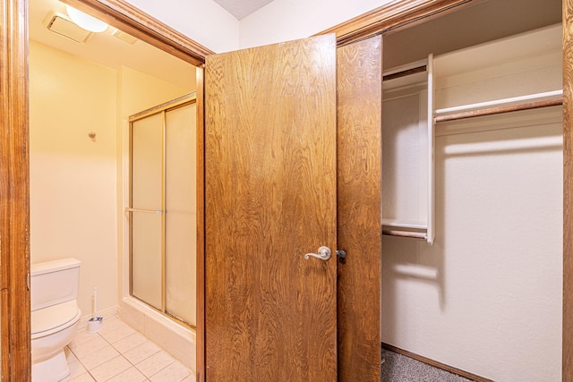 bathroom featuring tile patterned floors, an enclosed shower, and toilet