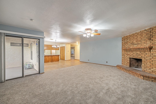 unfurnished living room featuring light carpet, a textured ceiling, ceiling fan with notable chandelier, and a brick fireplace