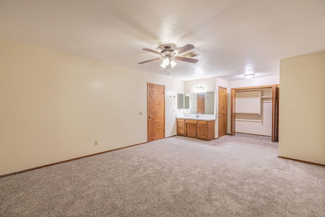 unfurnished bedroom with connected bathroom, ceiling fan, light colored carpet, a textured ceiling, and a closet