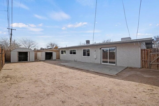 back of property with fence, a patio, stucco siding, a shed, and an outdoor structure