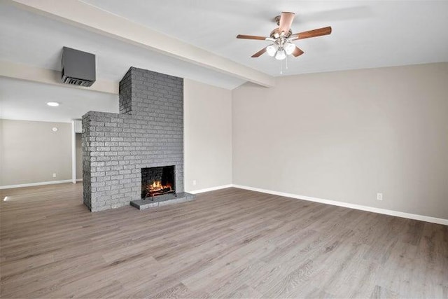 unfurnished living room with ceiling fan, a fireplace, wood finished floors, baseboards, and vaulted ceiling with beams