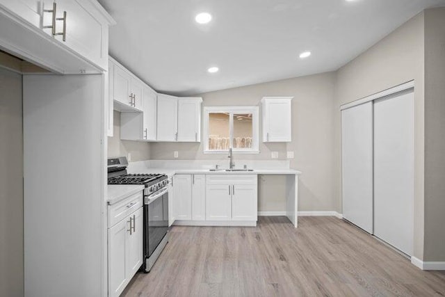 kitchen with stainless steel gas range, white cabinets, a sink, light wood-style flooring, and recessed lighting