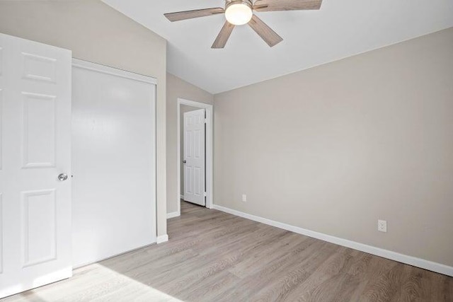 unfurnished bedroom featuring baseboards, ceiling fan, vaulted ceiling, and light wood-style flooring