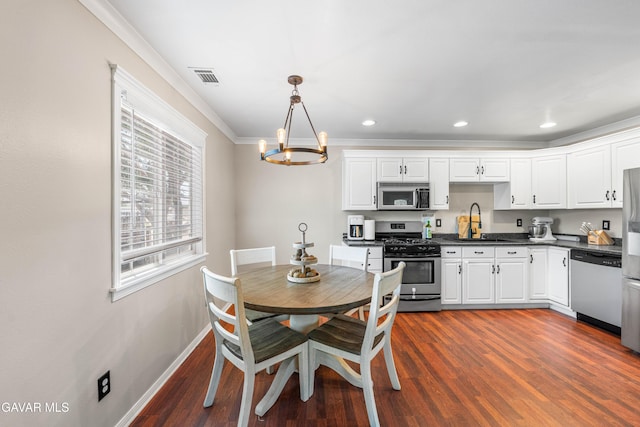 43249 W 42nd St, Lancaster, CA 93536 - kitchen with appliances with stainless steel finishes, dark countertops, a chandelier, crown molding, and white cabinets