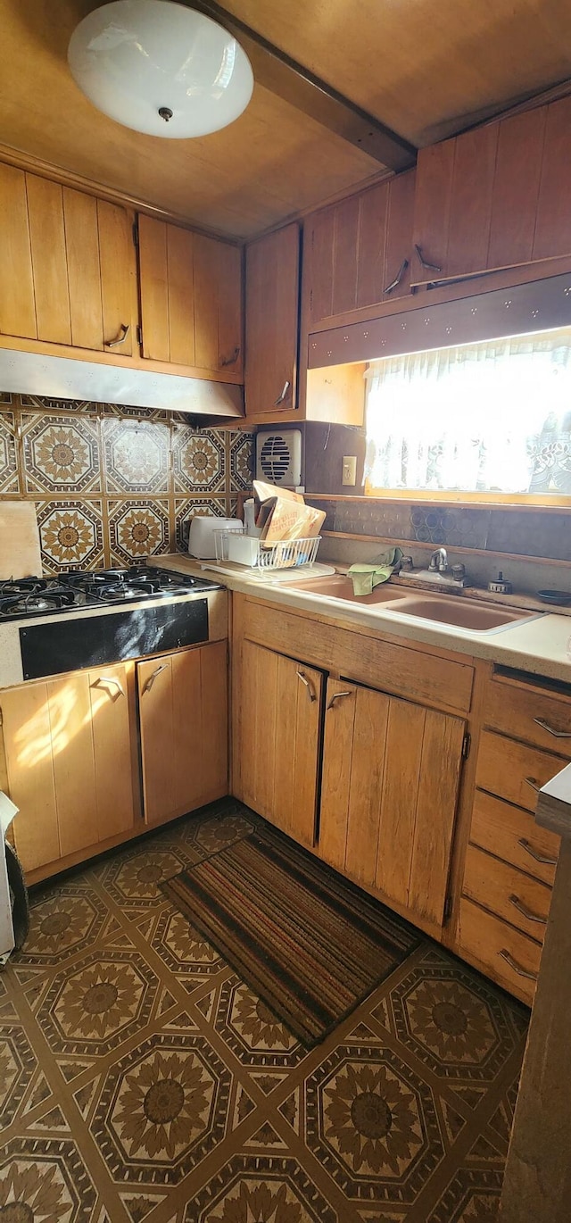 kitchen featuring gas cooktop, dark tile patterned flooring, sink, and decorative backsplash