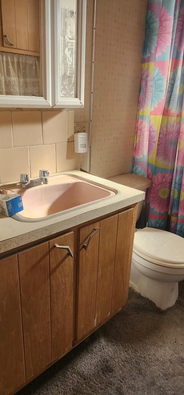 bathroom featuring tasteful backsplash, vanity, walk in shower, and toilet