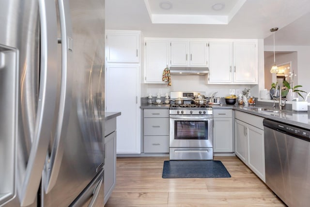 kitchen featuring sink, white cabinets, stainless steel appliances, and decorative light fixtures