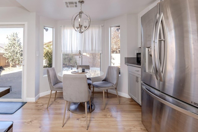 dining area featuring a wealth of natural light, light hardwood / wood-style flooring, and an inviting chandelier