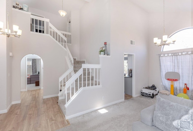 interior space with a notable chandelier, light hardwood / wood-style floors, and a towering ceiling