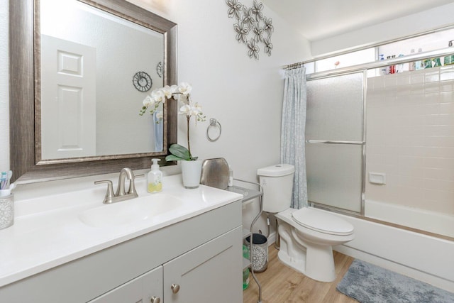 full bathroom featuring hardwood / wood-style flooring, vanity, toilet, and bath / shower combo with glass door