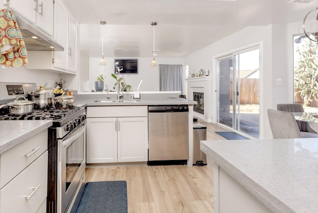 kitchen featuring white cabinets, hanging light fixtures, light wood-type flooring, and appliances with stainless steel finishes