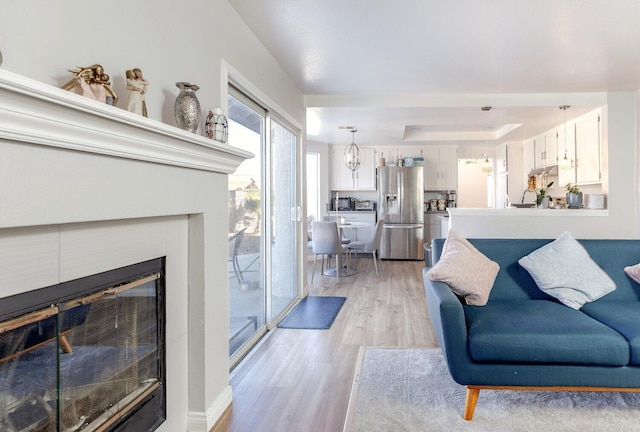 living room featuring a raised ceiling, light hardwood / wood-style floors, and a notable chandelier