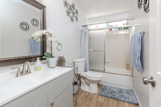 full bathroom featuring vanity, hardwood / wood-style flooring, toilet, and bath / shower combo with glass door