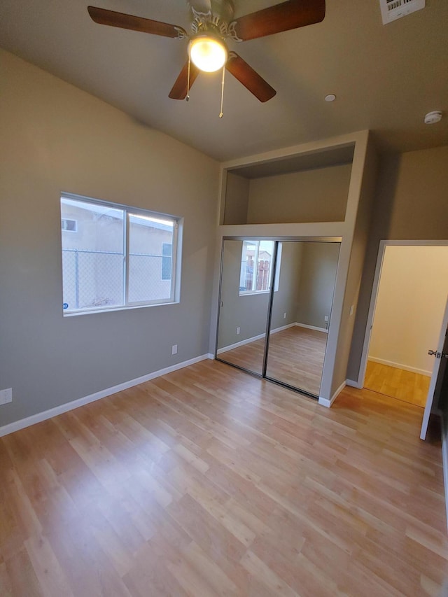 unfurnished bedroom featuring ceiling fan, light hardwood / wood-style floors, and a closet