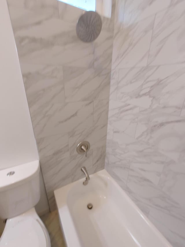 bathroom featuring tiled shower / bath and toilet