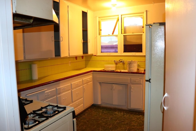 kitchen featuring sink, white appliances, and backsplash