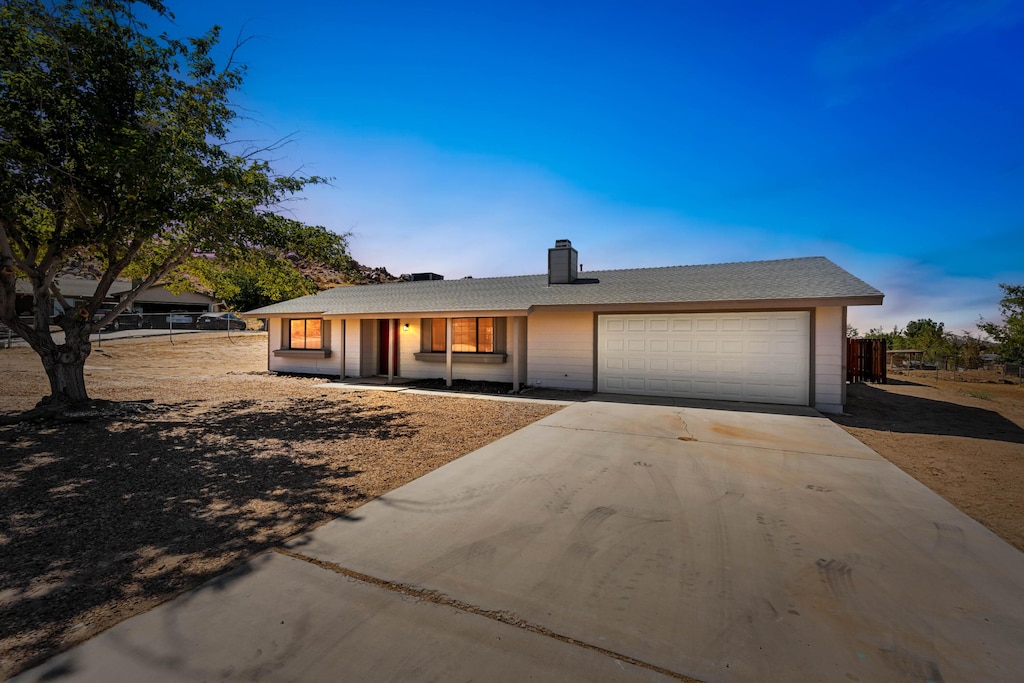 ranch-style house featuring a garage, driveway, and a chimney