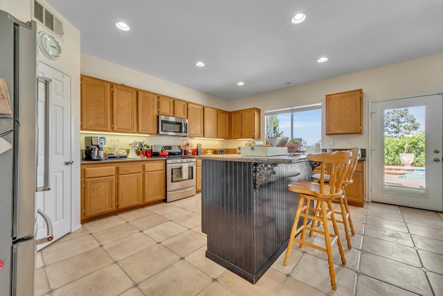 38360 Wakefield Pl, Palmdale, CA 93551 - kitchen featuring stainless steel appliances, recessed lighting, a kitchen bar, light tile patterned flooring, and a kitchen island