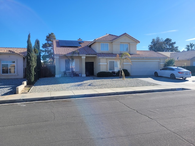 traditional home with solar panels, fence, a tile roof, driveway, and stucco siding