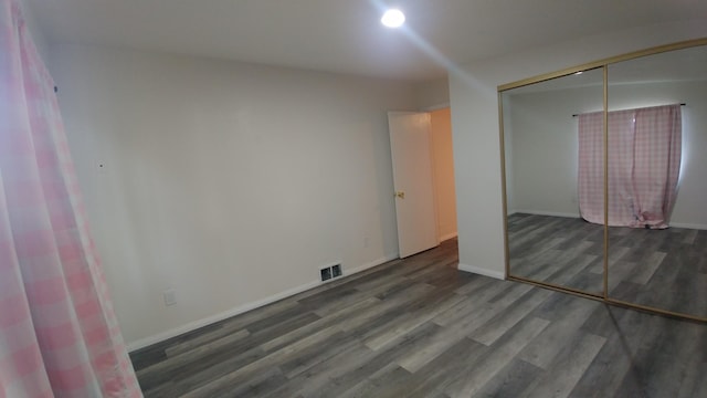 unfurnished bedroom featuring a closet and dark wood-type flooring