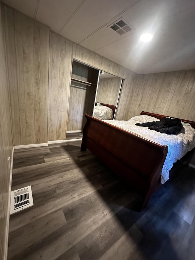 unfurnished bedroom with a closet, dark wood-type flooring, and wood walls