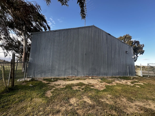 view of side of home featuring a lawn and an outbuilding