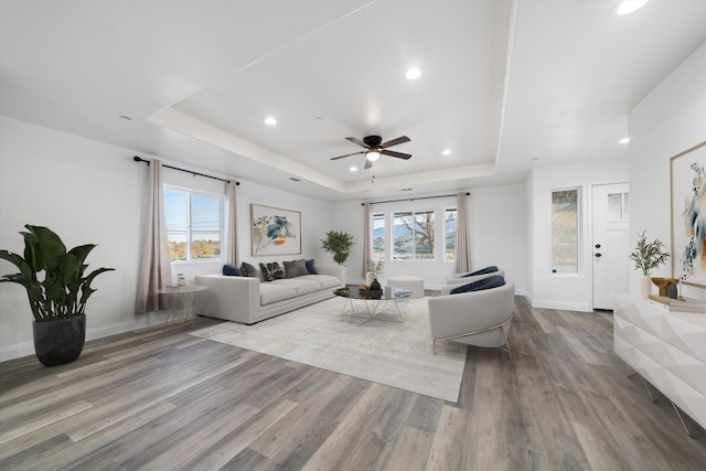 living area with a wealth of natural light, a raised ceiling, and wood finished floors