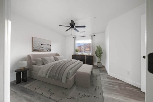 bedroom featuring visible vents, a ceiling fan, baseboards, and wood finished floors
