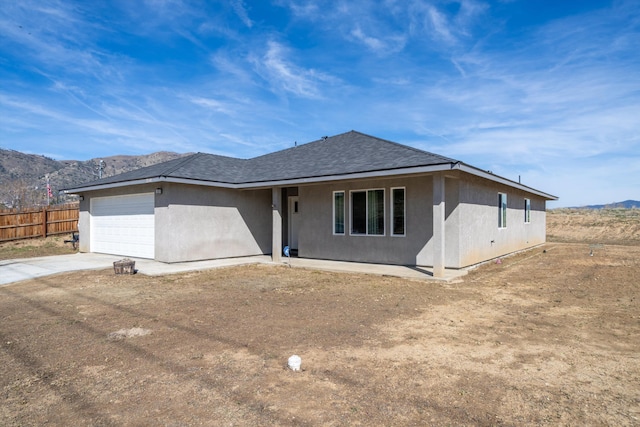 single story home with a mountain view, an attached garage, concrete driveway, and fence