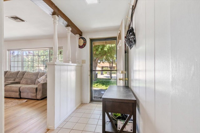 doorway featuring beam ceiling, light hardwood / wood-style flooring, and decorative columns