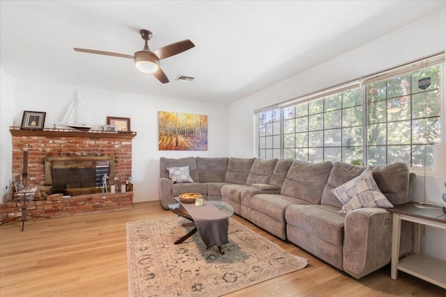 living room with hardwood / wood-style flooring, a brick fireplace, a healthy amount of sunlight, and ceiling fan