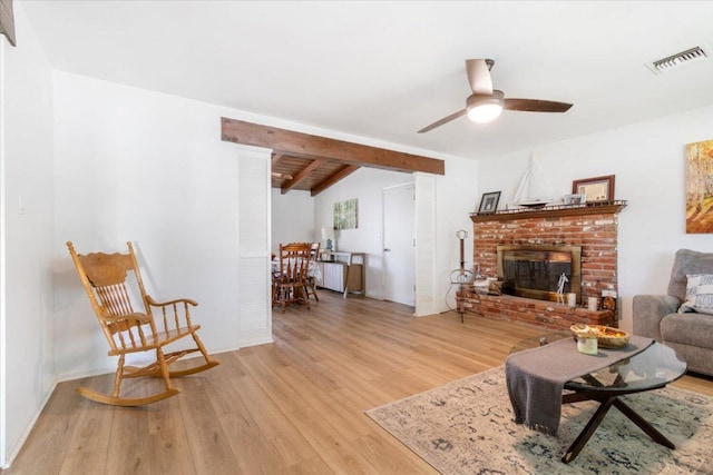 living room featuring a brick fireplace, light hardwood / wood-style floors, vaulted ceiling with beams, and ceiling fan