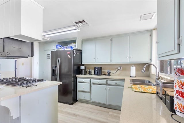 kitchen with stainless steel appliances, kitchen peninsula, sink, and light wood-type flooring