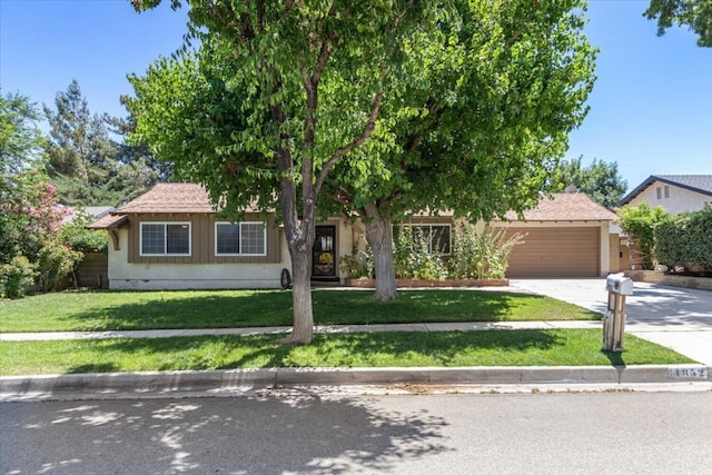 view of property hidden behind natural elements with a garage and a front lawn