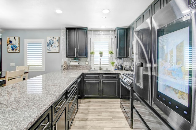 kitchen featuring stainless steel fridge with ice dispenser, sink, a wealth of natural light, and black / electric stove