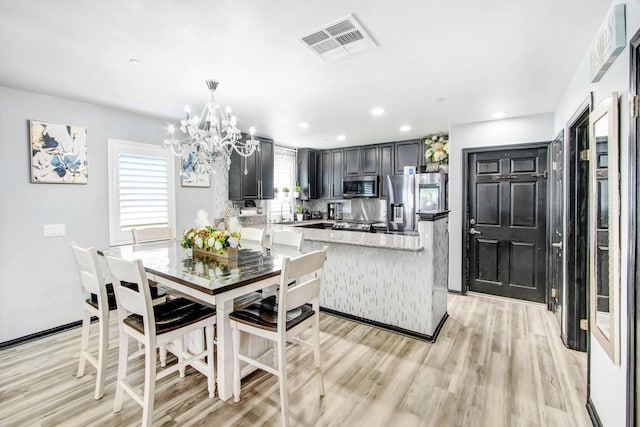 kitchen featuring plenty of natural light, light hardwood / wood-style floors, stainless steel appliances, and decorative light fixtures