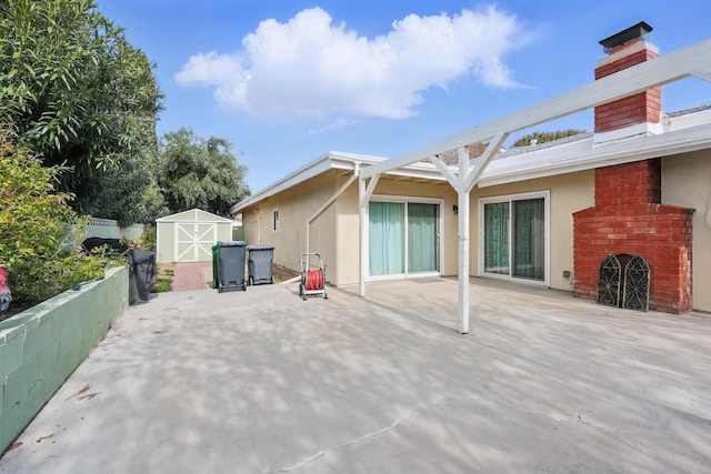 back of house featuring a storage shed, a chimney, a patio area, and stucco siding