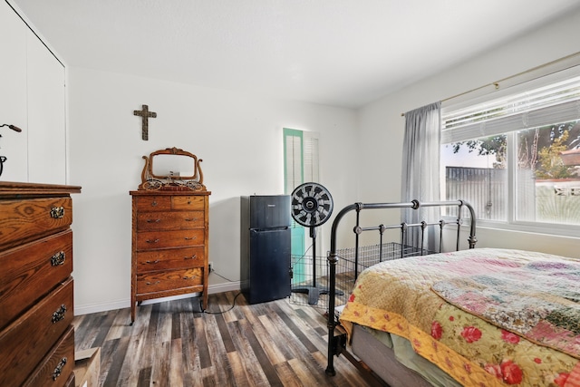 bedroom featuring baseboards, freestanding refrigerator, and wood finished floors