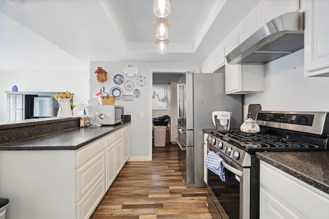 kitchen with wall chimney range hood, dark countertops, gas stove, wood finished floors, and white microwave
