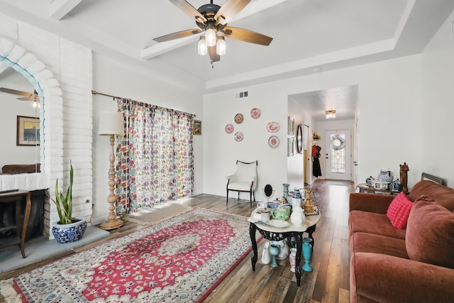 living room featuring a tray ceiling, a ceiling fan, wood finished floors, and visible vents