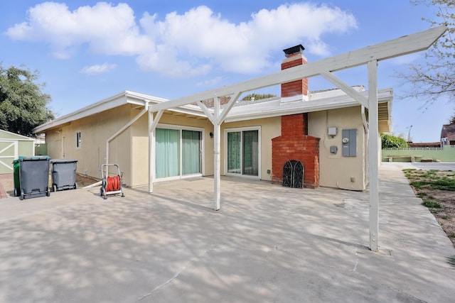 rear view of house featuring stucco siding, a chimney, and a patio area