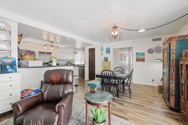 living room featuring baseboards, visible vents, an inviting chandelier, and light wood-type flooring