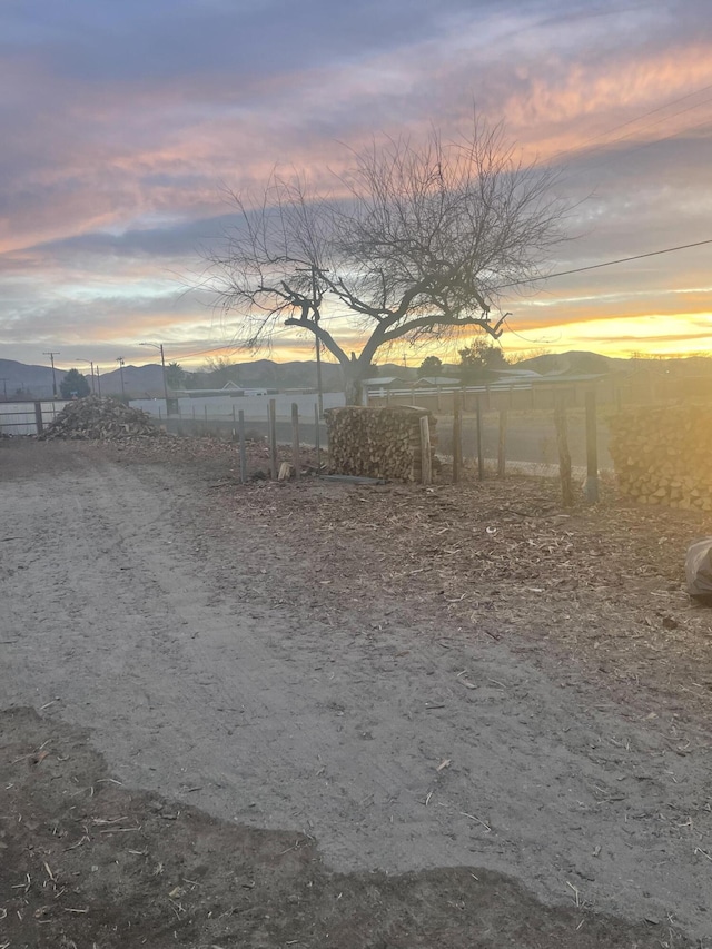 yard at dusk featuring a mountain view and a rural view