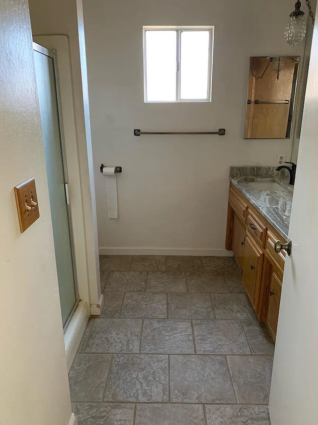 bathroom featuring a stall shower, baseboards, vanity, and stone finish floors