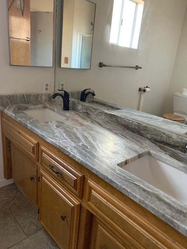 bathroom with double vanity and toilet