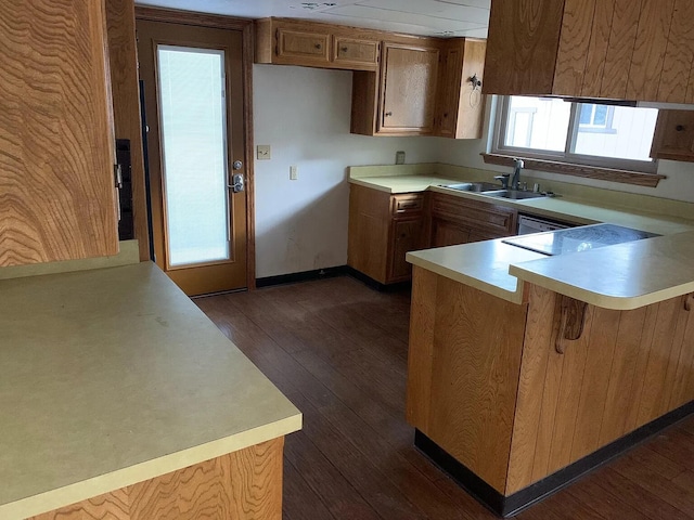 kitchen with a sink, a peninsula, dark wood finished floors, and light countertops