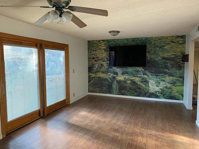 unfurnished room featuring wallpapered walls, hardwood / wood-style flooring, baseboards, a ceiling fan, and a textured ceiling
