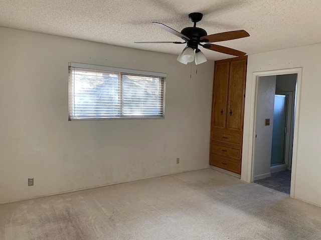 unfurnished bedroom featuring carpet, a textured ceiling, and a ceiling fan